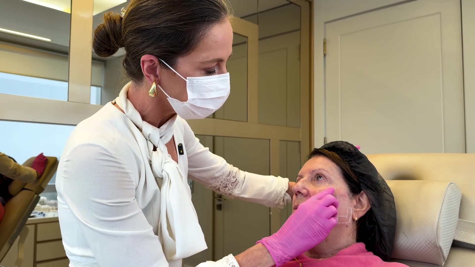 Médica trabalhando sobre a face marcada da paciente durante o procedimento
